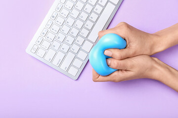 Female hands squeezing stress ball while working on color background
