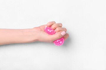 Female hand squeezing stress ball on white background