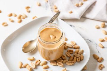 Obraz na płótnie Canvas Jar with tasty peanut butter on light background