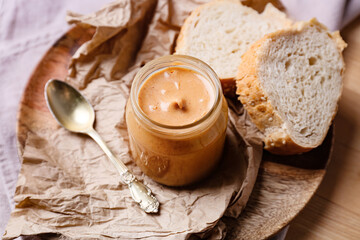 Obraz na płótnie Canvas Jar with tasty peanut butter and spoon on wooden background