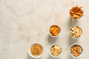 Bowls with tasty different crackers on light background