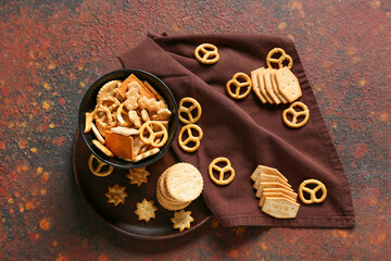 Bowl with tasty different crackers on grunge background