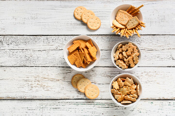 Fototapeta premium Assorted savory crackers and pretzel sticks in white bowls on rustic wooden table for snack time