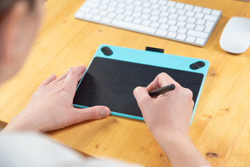 Hand of graphic designer working with stilus and tablet
