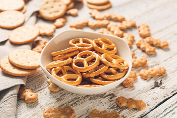 Bowl with tasty different crackers on light wooden background