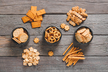 Bowls with tasty different crackers on wooden background