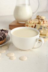 Cup with hot white chocolate on light background