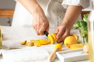 Obraz na płótnie Canvas Woman preparing ginger lemonade in kitchen