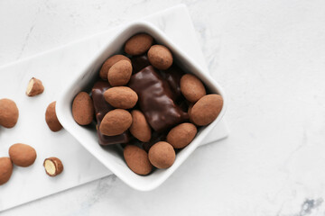 Bowl with tasty chocolate candies on light background, closeup