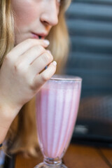 teen drinking pink smoothie drink in a cafe