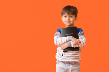 Little boy with Bible on color background
