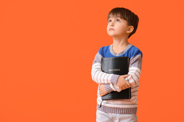 Little boy with Bible on color background