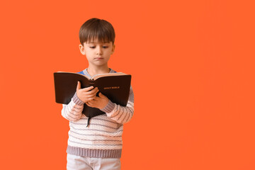 Fototapeta premium Little boy with Bible on color background