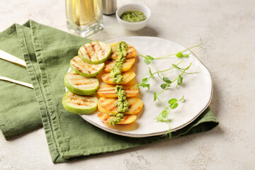 Tasty grilled vegetables with pesto sauce on light background