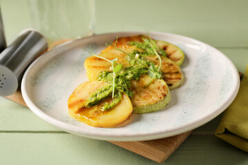 Tasty grilled vegetables with pesto sauce on color wooden background, closeup