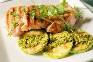 Plate with tasty grilled chicken meat, zucchini and pesto sauce, closeup