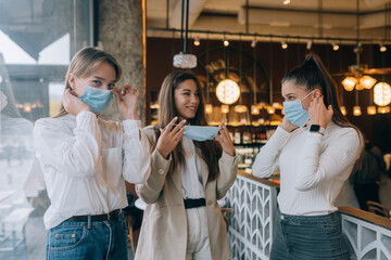 Caucasian women taking off a medical mask in a cafe