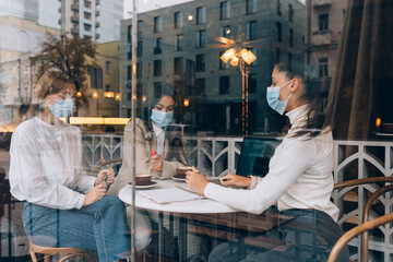 Friends girls met in a cafe. Wear medical protective masks.