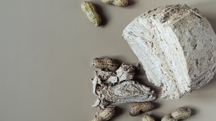 Peanut halva and peanut nuts on a light brown background top view of kopi space. Halva oriental sweets	