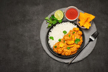 Plate of Traditional Chicken Curry, nachos and rice on stone serving board