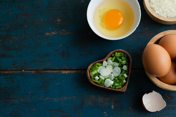 Multiple eggs in a cup with garlic and onions lay on a vintage wooden floor.