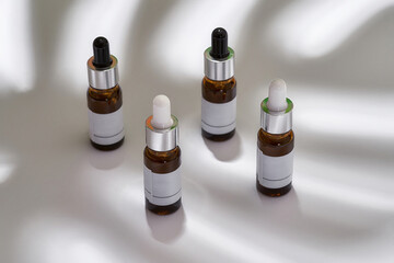 Pipette bottles with essential oils under leaf shadow