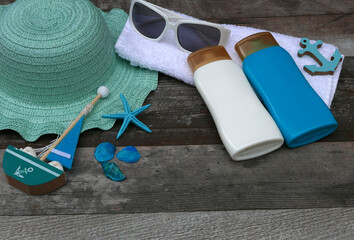 Beach accessories: sunscreen sunglasses and a sun hat on a towel.