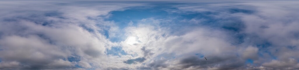Blue evening sky seamless panorama spherical equirectangular 360 degree view with Cumulus clouds, setting sun. Full zenith for use in 3D graphics, game and aerial drone panoramas as sky replacement.