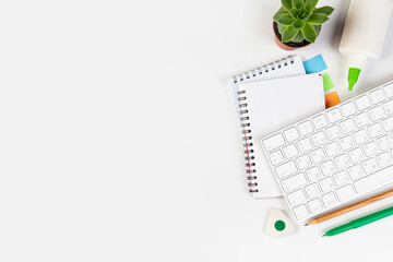 Flat lay, office table top view. Workspace with blank notebook, keyboard, stationery, pencil, succulent in a pot on a white background.