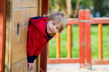 Cute toddler child, blond boy, playing on the playground