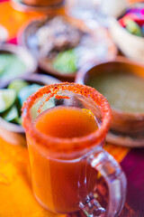 Traditional Mexican michelada in glass mug with blurry background