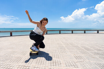 Fototapeta na wymiar Young asian women riding surfskate board. Trendy outdoor sport in Thailand, Asia.