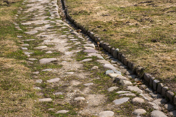 Obraz premium Ancient road paved with cobblestones. Drainage ditch.