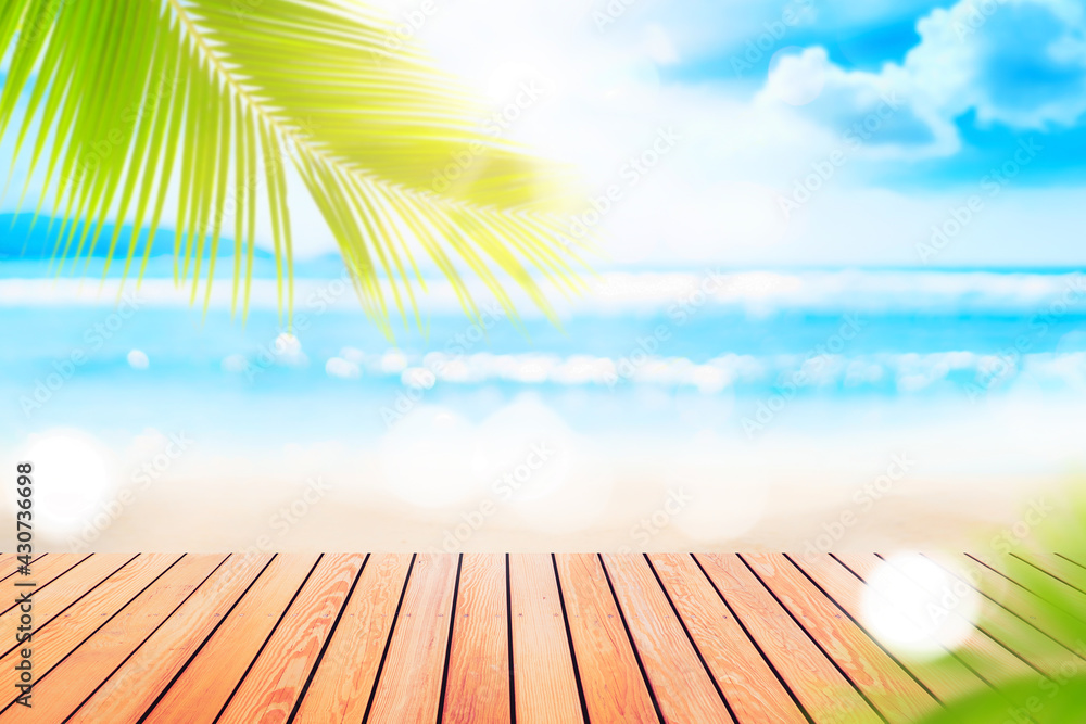 Poster blur tropical beach with bokeh sun light wave and palm tree on empty old wood table abstract backgro
