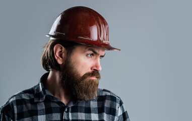 bearded male hipster in checkered shirt and laborer helmet, tool shop