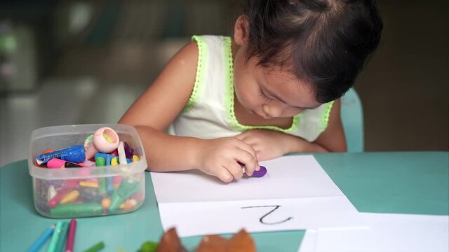 Cute Thai Girl is drawing on paper indoor.
