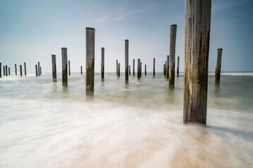 Long exposure seascape. Taken at the North Sea in Petten with the pole village in the sea, Blue sky, sun and shodows. Focus on foreground