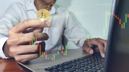 Bitcoin gold coin and defocused chart background. Business man with bitcoins. Virtual cryptocurrency concept.