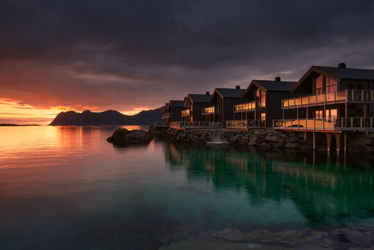 Houses on the rocky shore of the Norwegian sea during a red sunset