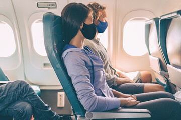 Couple tourists wearing face masks on travel vacation flight inside plane. Coronavirus safety...