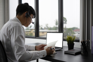 Young man employee in headset using laptop computer and take part in distant virtual briefing video conference .