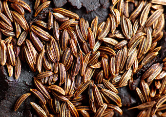 Cumin seeds on rye bread as background.