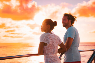Sunset cruise romantic couple watching view from boat deck on travel vacation. Silhouette of man and woman tourists relaxing on outdoor balcony of ship.