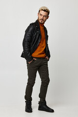 stylish man in leather jacket turned aside orange sweater in blond trousers