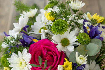 Close up bouquet with red rose, purple irises and white, yellow, green chrysanthemums. floral background.