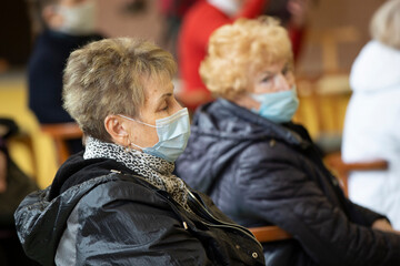 A group of elderly people wearing medical masks at a meeting or at a nursing home during a coronavirus epidemic.