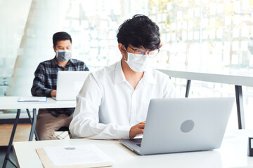 Fototapeta premium Business people with protective face masks are working in the office.keeping a distance during COVID-19 pandemic . social distancing concept.