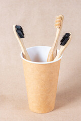 Fototapeta na wymiar Eco friendly bamboo toothbrushes in cup on brown background. Zero waste concept