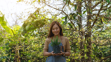 A young asian woman holding and preparing to plant rosemary tree for home gardening concept