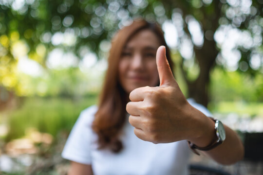 Closeup image of a woman making and showing thumbs up hand sign
